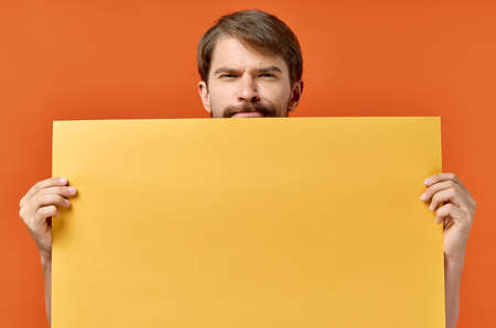 emotional man holding a yellow banner design orange backgroundの写真素材