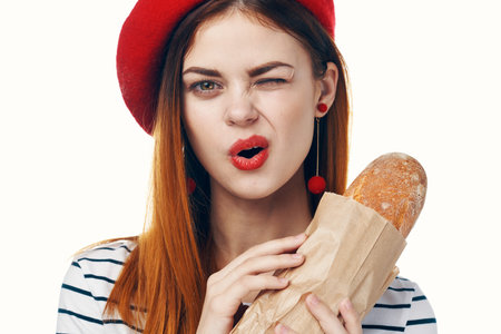 pretty french woman holding a loaf of striped t-shirt light backgroundの写真素材