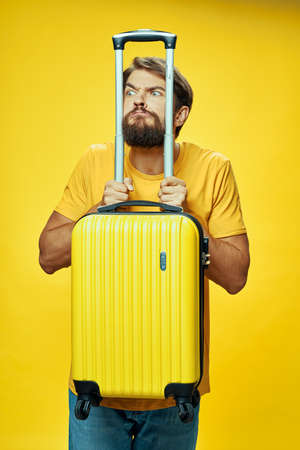 man leaning his elbows on a yellow suitcase with his hands travel tourismの写真素材