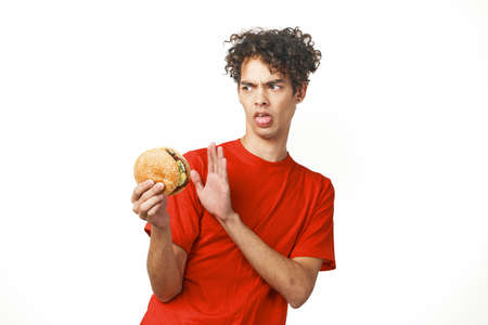 Cheerful curly hamburger guy holding a red t-shirt lifestyleの写真素材