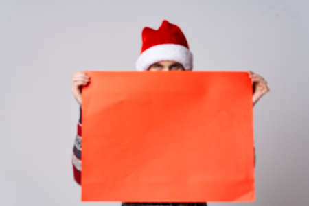 Cheerful man in a christmas hat with Red mockup poster light backgroundの写真素材