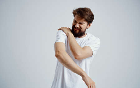 emotional man in a white t-shirt stress medicine pain in the neck isolated backgroundの写真素材