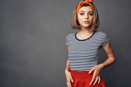pretty fashionable woman with orange headband red skirt posingの写真素材