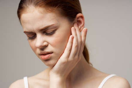 sick woman poor hearing disorders in white t-shirts light backgroundの写真素材