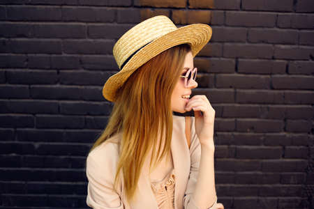 pretty woman on the street wearing hat and glasses black brick wall