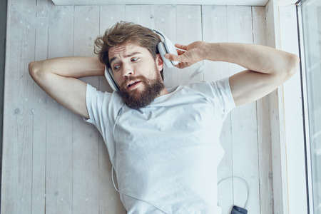 cute man lying near the window wearing headphones fashionの写真素材