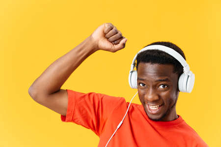 Cheerful man in headphones and gesturing with his hands dance music yellow backgroundの写真素材
