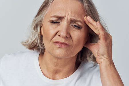 elderly woman holding her head migraine pain treatmentの写真素材
