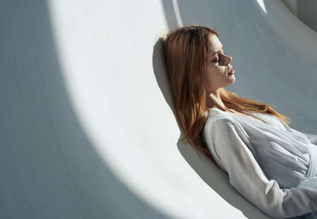cute red-haired woman in a white robe lies on a white background