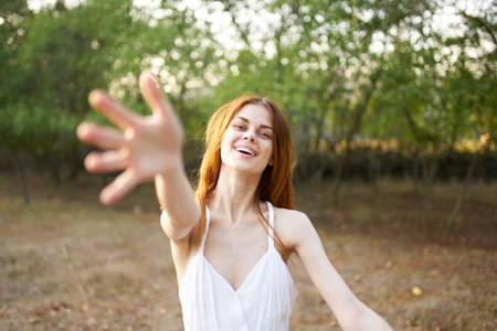cheerful woman in a white dress in the field nature emotions freedomの写真素材