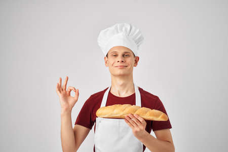 a man in a white apron with a loaf in the hands of a professional baking