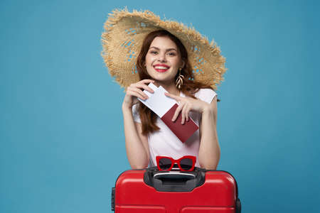 woman with hat red suitcase vacation flight airport blue backgroundの写真素材