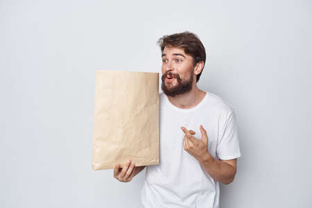 man with paper bag in hands mockup shopping emotions light backgroundの写真素材
