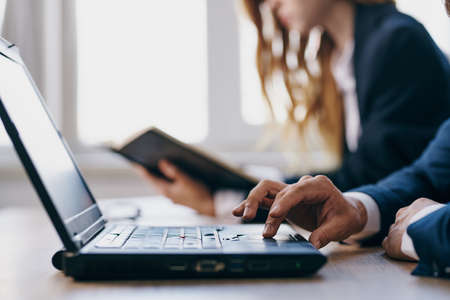 business man and woman sitting at a desk with a laptop communication finance officialsの写真素材