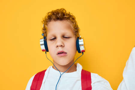 boy with curly hair wearing headphones listening to musicの写真素材