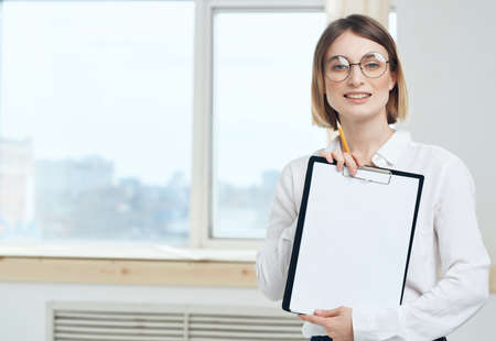 Business woman in white shirt and glasses near office manager windowの写真素材