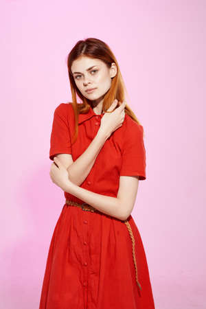 red-haired woman in red dress posing attractive look pink backgroundの写真素材
