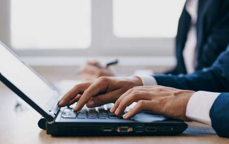 colleagues sitting at a desk with a laptop communication finance professionalsの写真素材