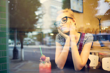 woman sitting in a cafe cocktail looking out the window leisure lifestyleの写真素材