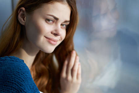 beautiful woman sitting on the windowsill with a blue plaid smileの写真素材