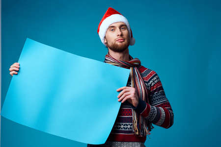 handsome man in a santa hat holding a banner holiday blue backgroundの写真素材
