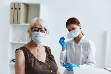 elderly woman wearing a medical mask in the hospital for vaccinationsの写真素材