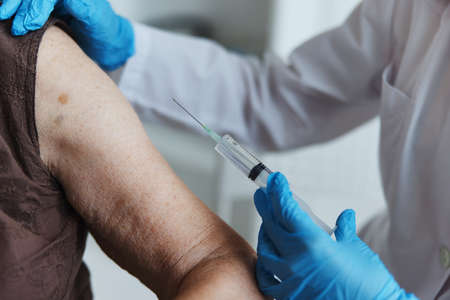nurse makes an injection in the arm covid-19 passport close-upの写真素材