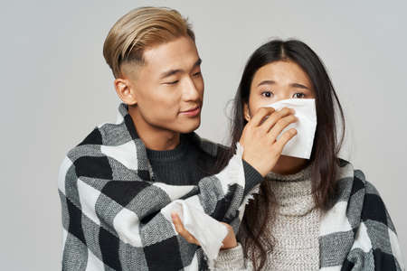 a man in warm clothes caring for a sick Asian womanの写真素材