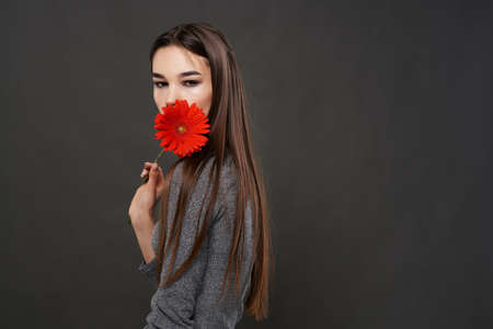 pretty brunette red flower near face makeup dark backgroundの写真素材