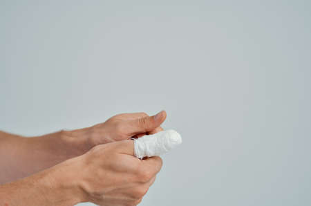 sick man in a white T-shirt with a bandaged hand isolated backgroundの写真素材