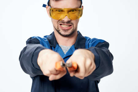 male builder in yellow construction glasses emotions light background