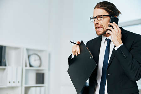 man in a suit documents in hand communication by phone executiveの写真素材