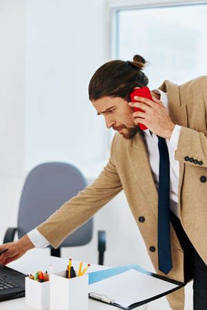 man in beige jacket in the office with a laptop lifestyleの写真素材