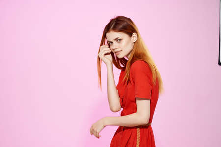 pretty woman in red dress posing attractive look pink backgroundの写真素材