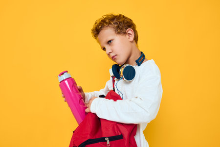 teenager with a red backpack wearing headphones yellow backgroundの写真素材