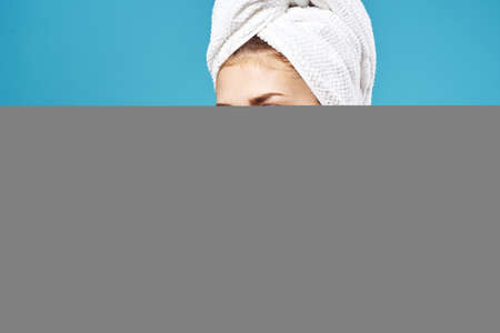 woman with towel on head cleaning face skin care blue backgroundの写真素材
