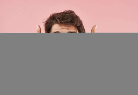 Cheerful man in a white t-shirt gesturing with his hands pink backgroundの写真素材