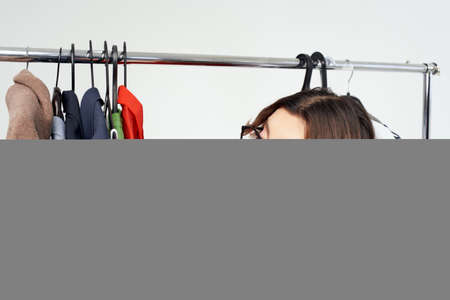 pretty woman with glasses trying on clothes shop shopaholic light backgroundの写真素材
