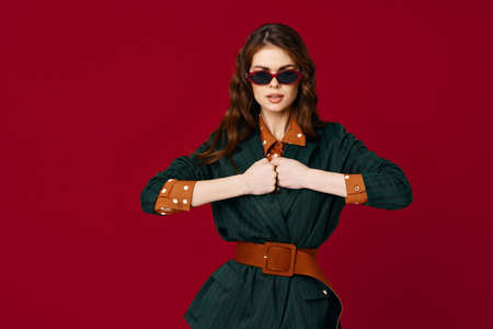 fashionable woman in suit gesturing with hands sunglasses luxury red backgroundの写真素材