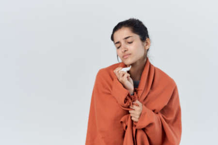 sick woman with a blanket on her shoulders a cold infectionの写真素材