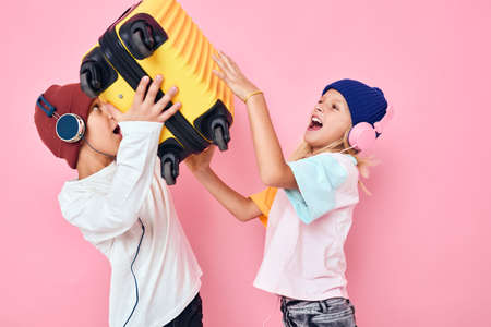Portrait of a girl and a boy with a yellow suitcase in his hands isolated backgroundの写真素材