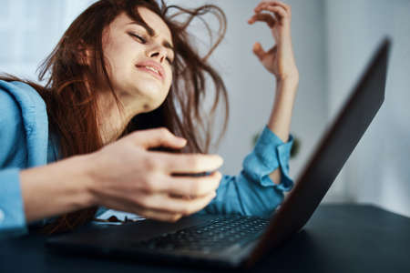 disgruntled woman in front of laptop upset work fatigueの写真素材