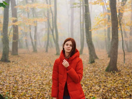 woman in a red jacket in the forest on nature fog travelの写真素材