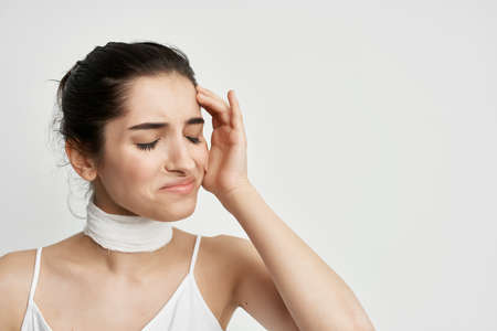 woman bandaged neck negative headache light backgroundの写真素材
