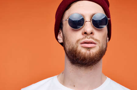 Cheerful man in sunglasses holding a flower orange backgroundの写真素材