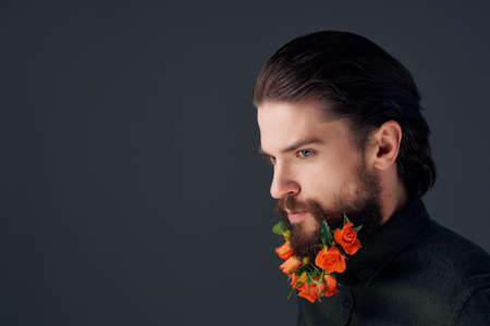 portrait of a man posing flowers in a beard fashion dark backgroundの写真素材