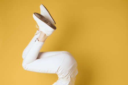 woman in fashionable clothes shoes posing studio yellow backgroundの写真素材