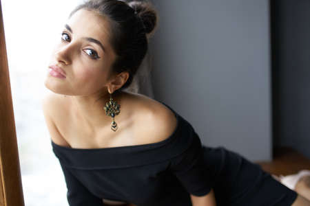 beautiful woman in a black dress near the window posing elegant style