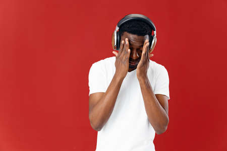 man wearing headphones holding his face technology music red backgroundの写真素材