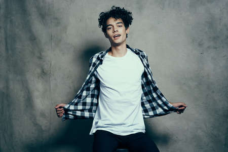 cute guy in a plaid shirt sitting on a chair posing studioの写真素材